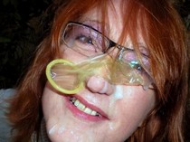 Sperm and condom on redhead matures face.